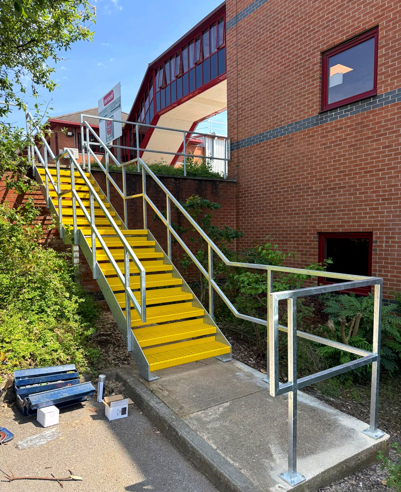 Galvanised steel fire escape staircase with yellow open-mesh treads at Eurocell head office, Alfreton